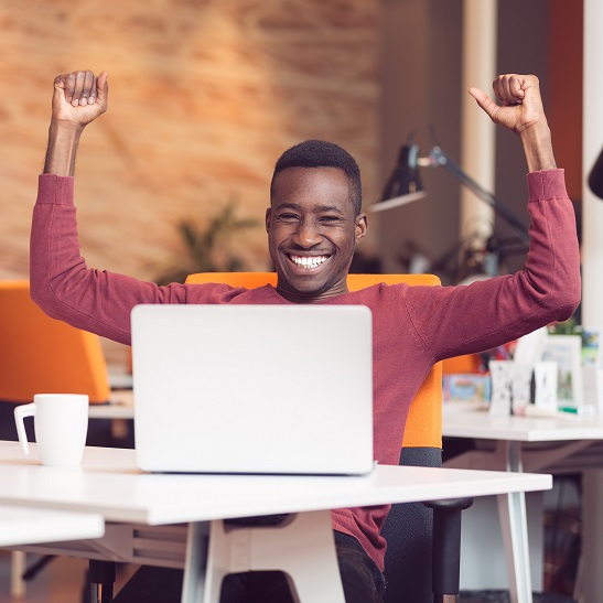 Happy successful African American businessman in a modern startup office indoors Happy smiling successful African American businessman in a modern startup office indoors